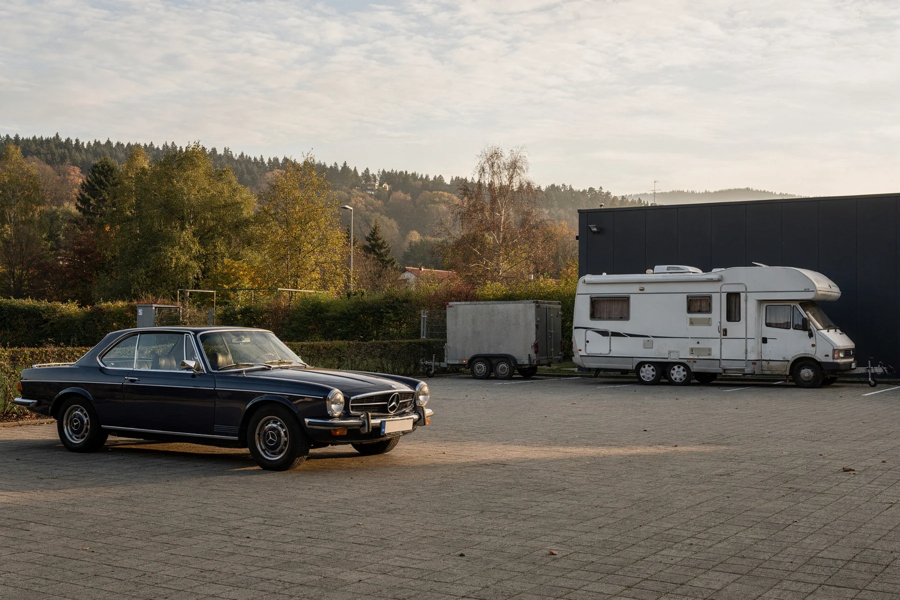 Illustratives Motiv: Oldtimer und Wohnmobil auf einer Stellfläche